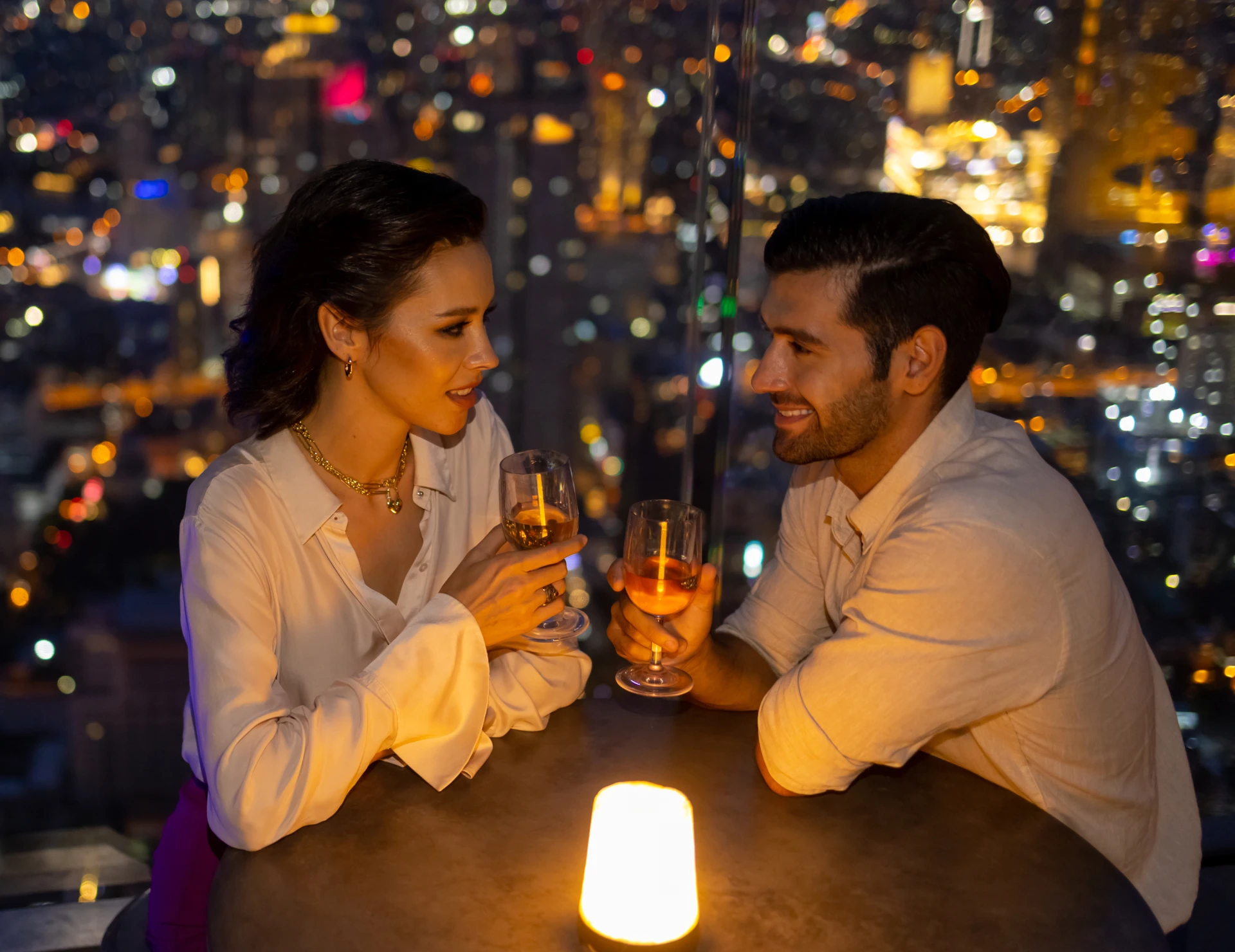 Couple enjoying drinks at rooftop bar.