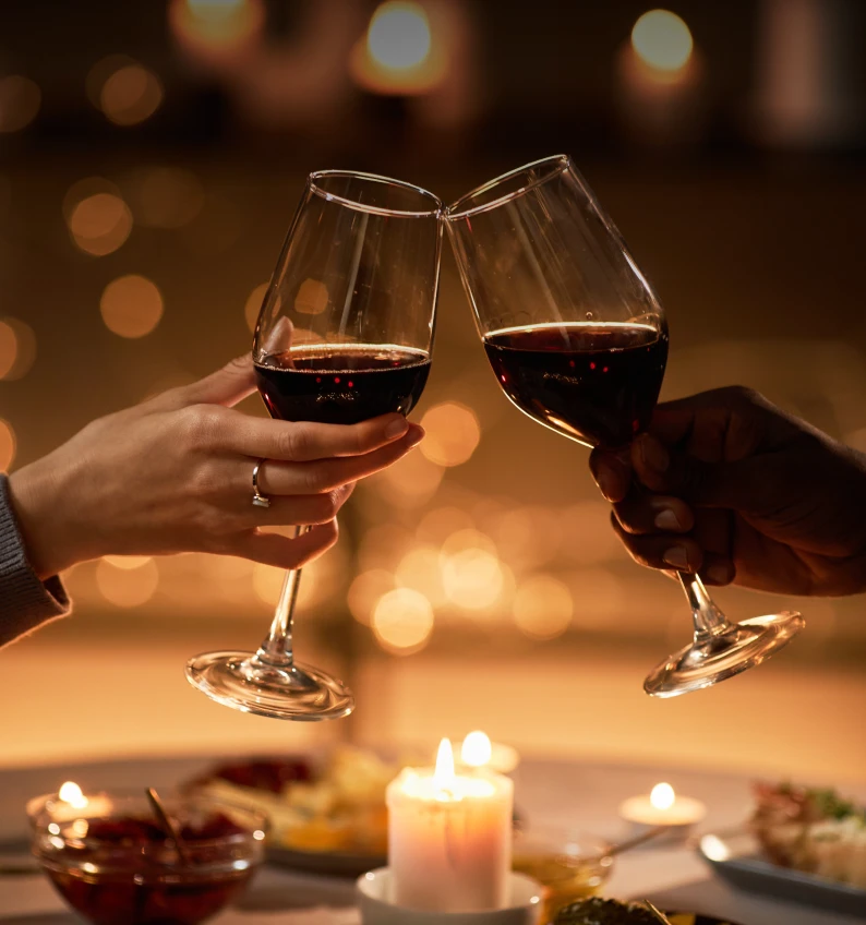 Toasting wine glasses in candlelit setting.