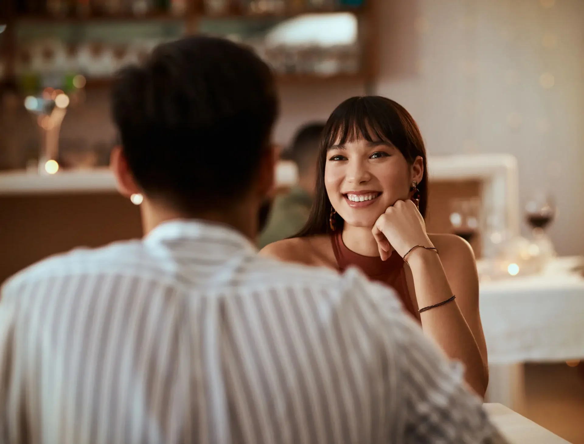 A woman smiling warmly at a man across the table in a cozy setting.