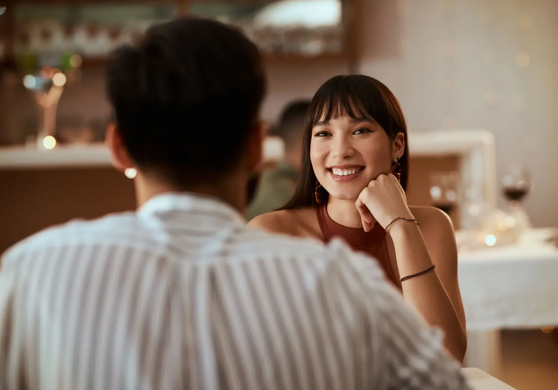 A woman smiling warmly at a man across the table in a cozy setting.