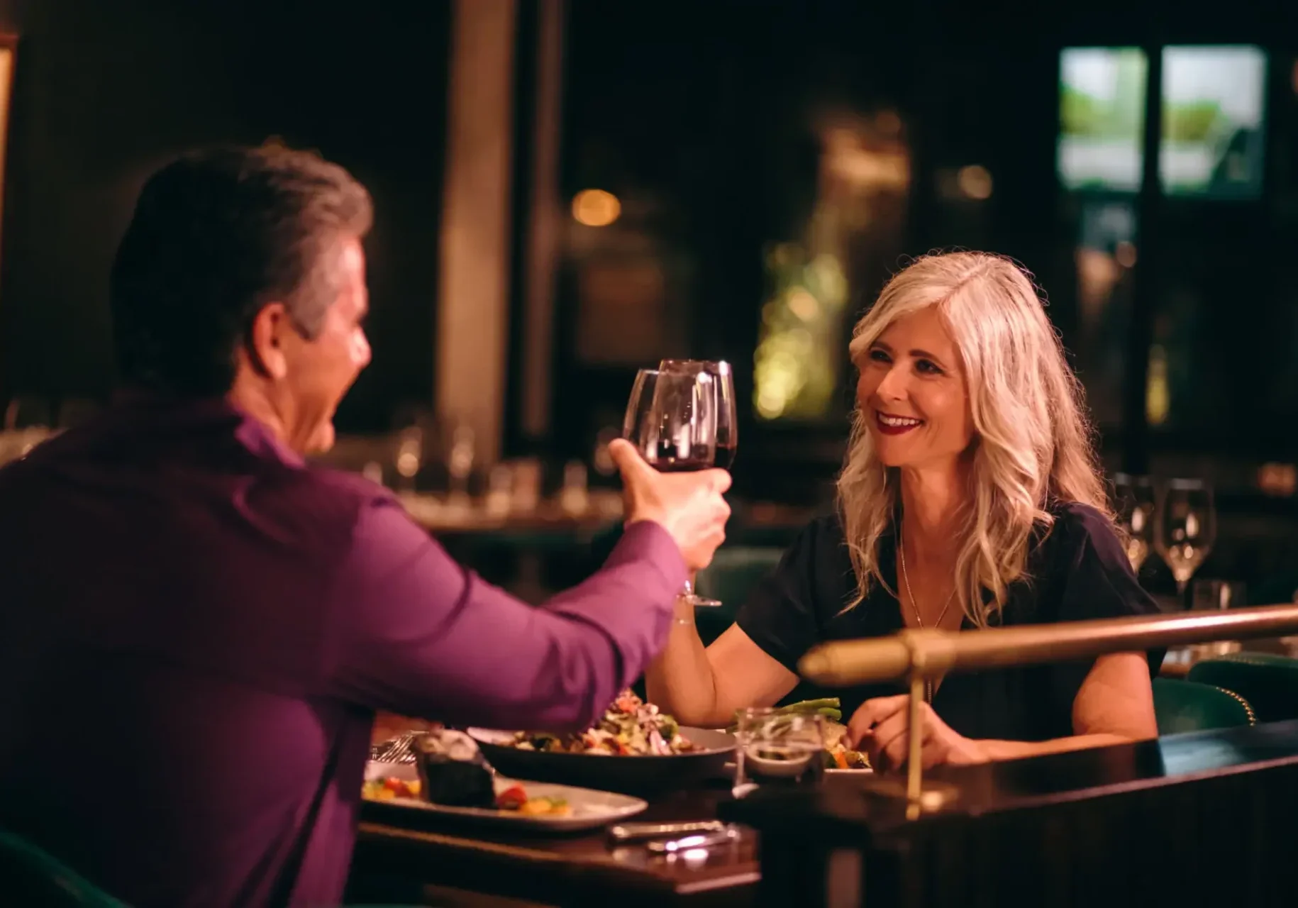 Couple enjoying a romantic dinner with wine at a cozy restaurant.